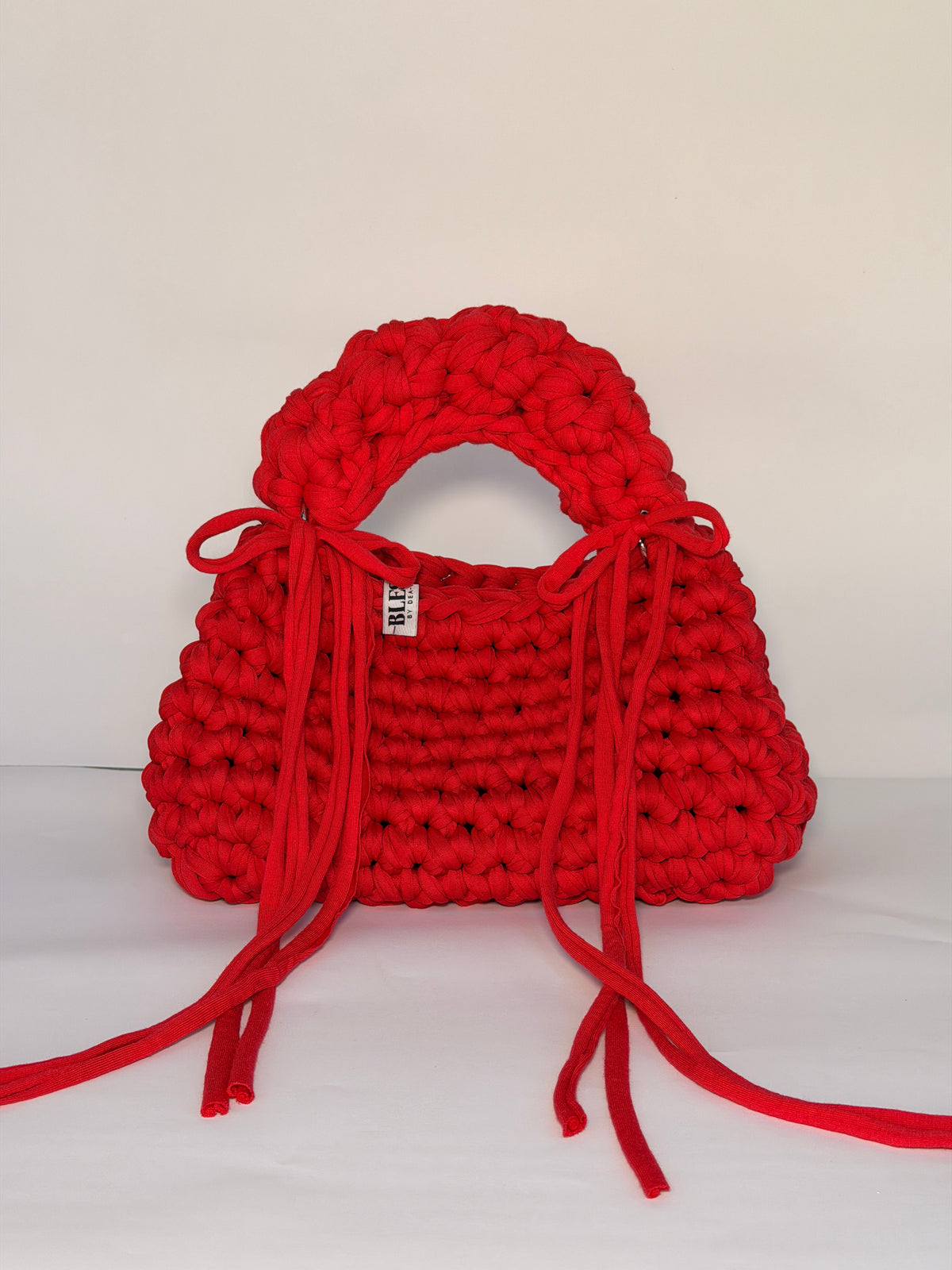 Bright red bobble-stitch crochet bag with a chunky top handle and bows at each side