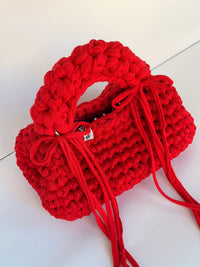 Bright red bobble-stitch crochet bag with a chunky top handle and bows at each side