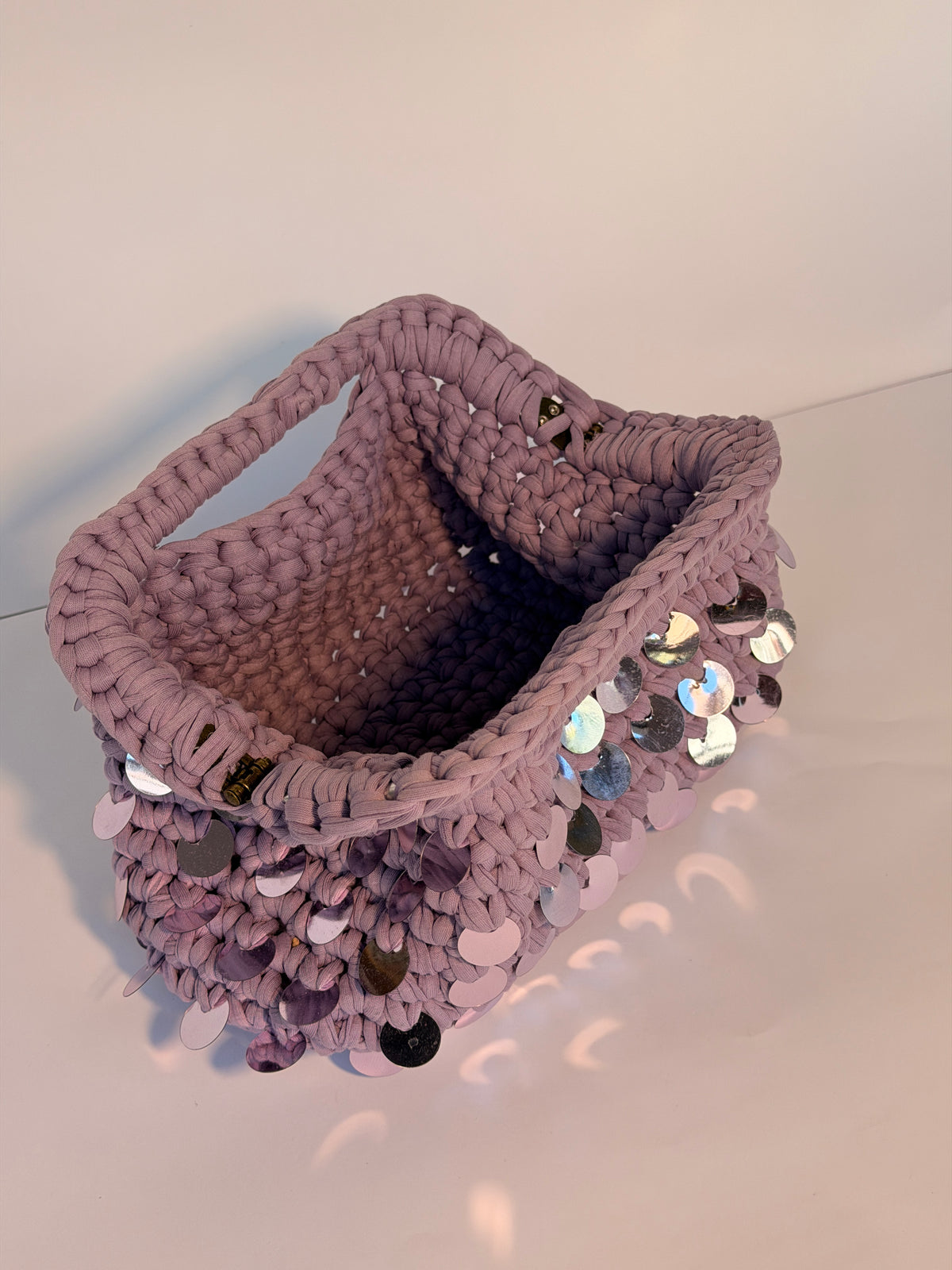 Dusty lilac crochet clutch covered in iridescent paillettes with an integrated top handle