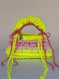 Neon yellow bobble-stitch crochet bag banded with blush, with a chunky top handle and bows