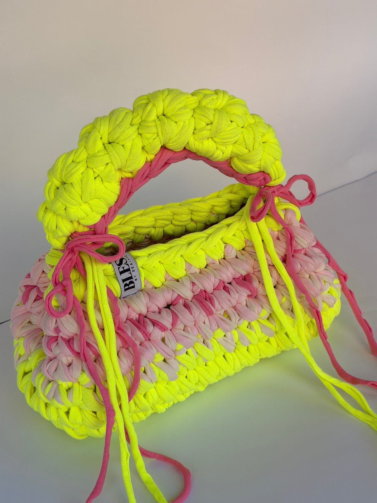 Neon yellow bobble-stitch crochet bag banded with blush, with a chunky top handle and bows