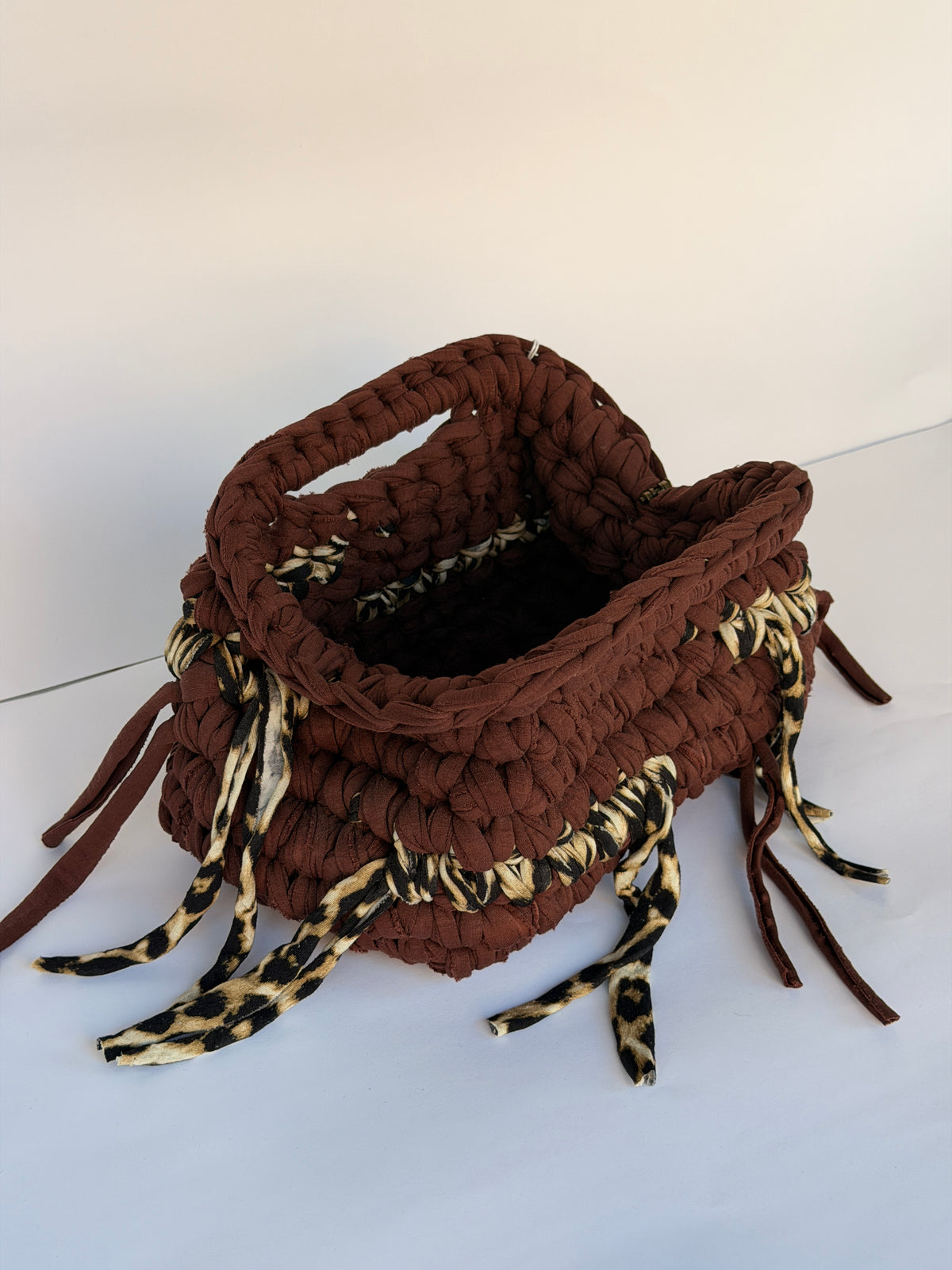 Warm brown crochet clutch with a leopard-print fringe and integrated top handle