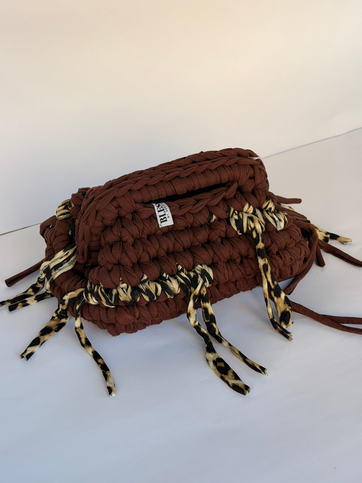 Warm brown crochet clutch with a leopard-print fringe and integrated top handle