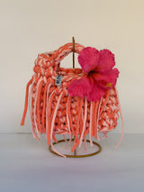 Coral and blush crochet bag with a braided top handle, long fringe and a pink hibiscus flower
