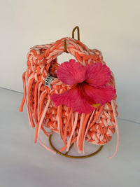 Coral and blush crochet bag with a braided top handle, long fringe and a pink hibiscus flower