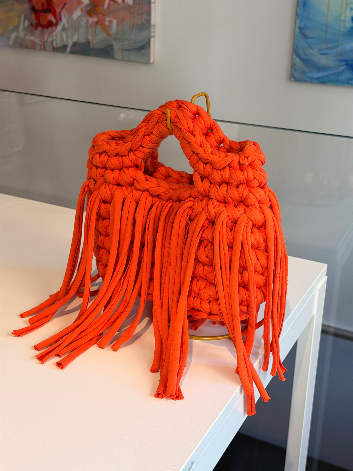 Bright orange crochet bag with a chunky braided top handle and a long fringe