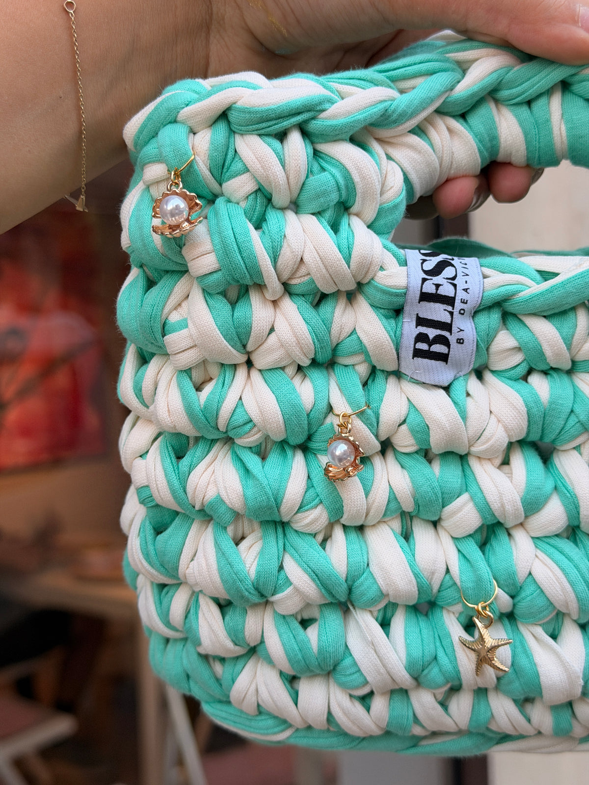 Seaglass green and cream striped crochet bag with a braided top handle and gold shell charms