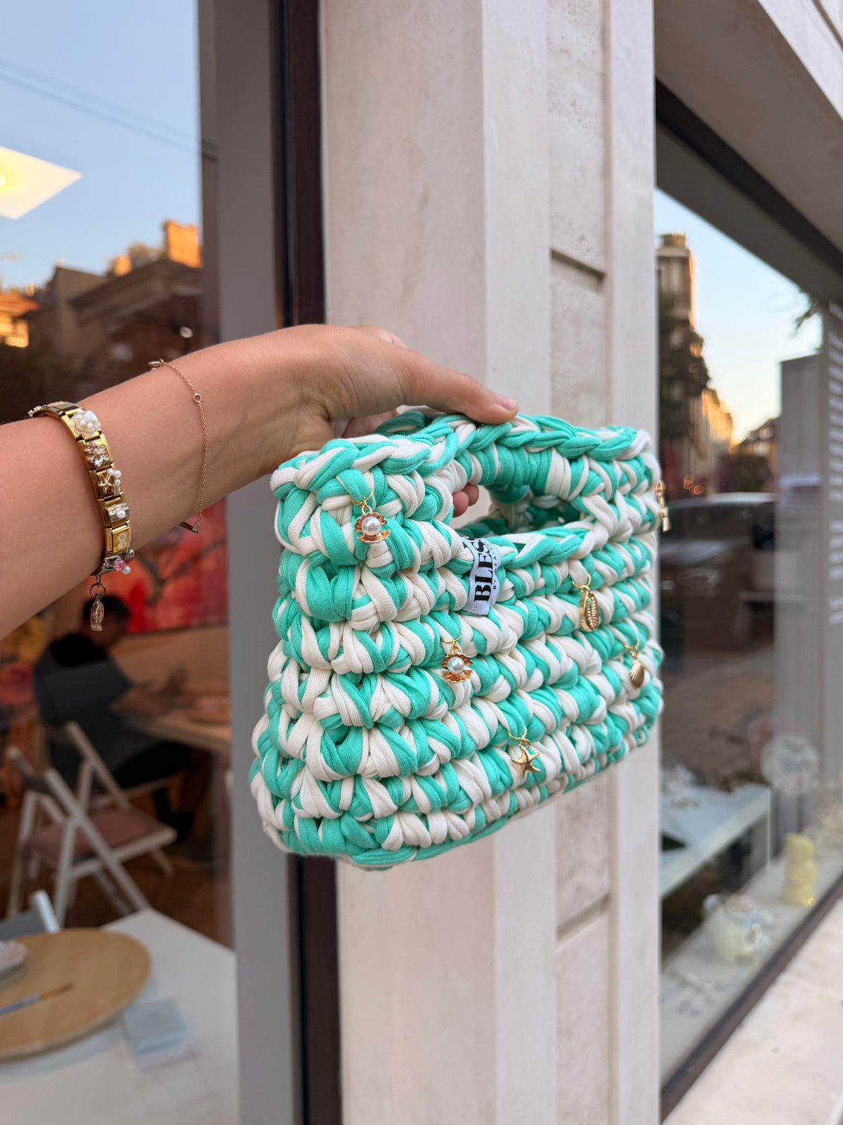 Seaglass green and cream striped crochet bag with a braided top handle and gold shell charms