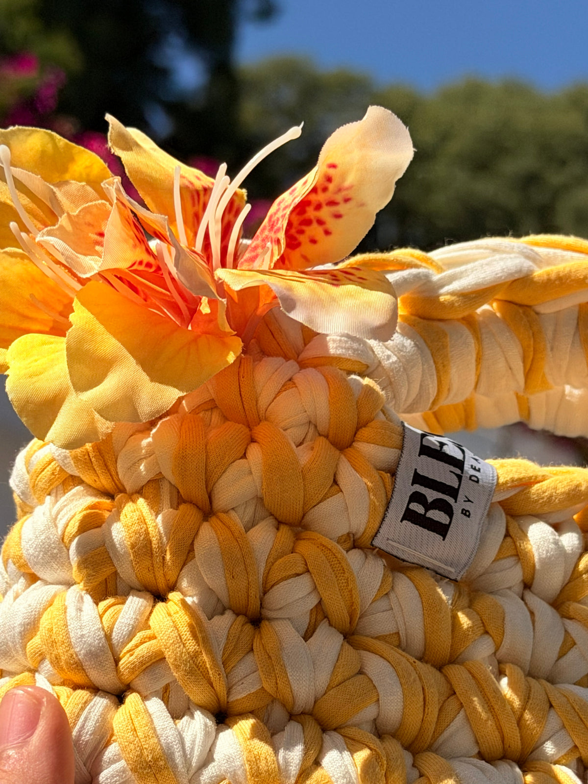 Golden yellow and cream crochet bag with a braided top handle and a yellow flower
