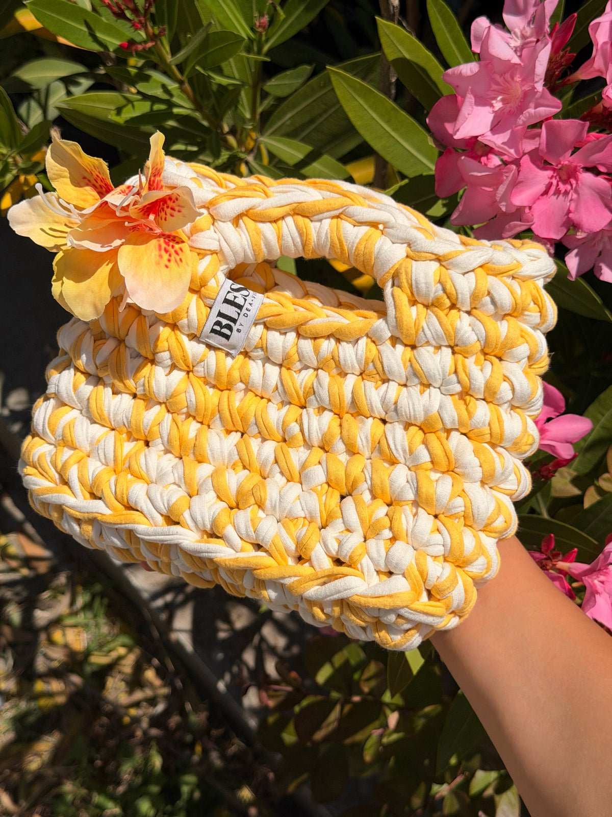 Golden yellow and cream crochet bag with a braided top handle and a yellow flower