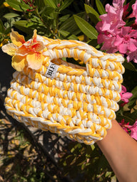 Golden yellow and cream crochet bag with a braided top handle and a yellow flower