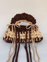 Brown and cream crochet bag with a braided top handle and long ties tied in bows