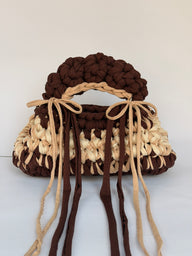 Brown and cream crochet bag with a braided top handle and long ties tied in bows