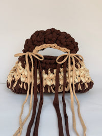 Brown and cream crochet bag with a braided top handle and long ties tied in bows