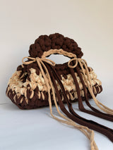 Angled view of a brown and cream crochet bag in a deep bobble stitch with long trailing ties