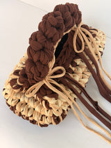 Close view of the braided brown top handle and gold ring on a cream and brown crochet bag