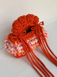 Top view of the bobbled orange handle and bows on an orange and pink crochet bag