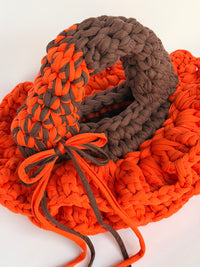 Bright orange crochet bag with a deep brown collar, two arc handles and long orange and brown ties