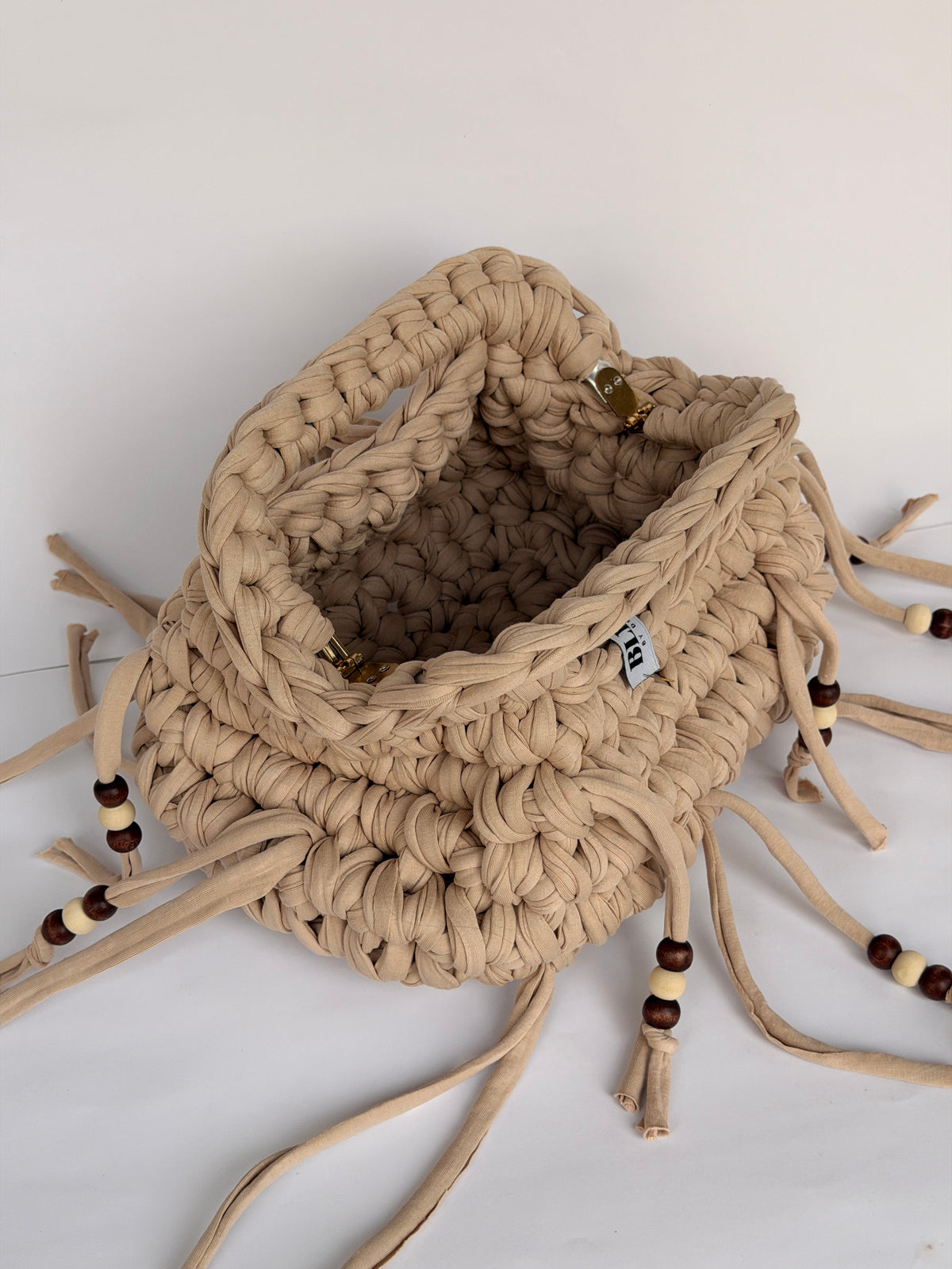 Open top of a sand coloured crochet clutch showing the woven Blessed label inside