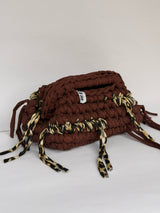 Side view of a warm brown crochet clutch showing the leopard print row worked into the base