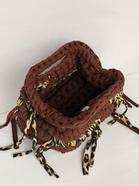 Warm brown crochet clutch with a leopard print band and leopard ties, woven Blessed label visible