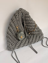 Close view of the snakeskin mini bag charm clipped to a grey crochet origami bag