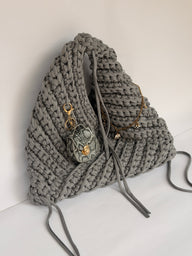 Close view of the snakeskin mini bag charm clipped to a grey crochet origami bag