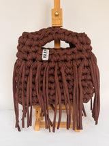 Angled view of a deep brown crochet bag with a long fringe falling past the base