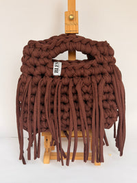 Angled view of a deep brown crochet bag with a long fringe falling past the base