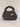 Top view of a charcoal grey chunky crochet bag with a gold charm brooch on the rim