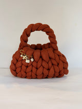Close view of the gold charm brooch on a rust chunky crochet bag