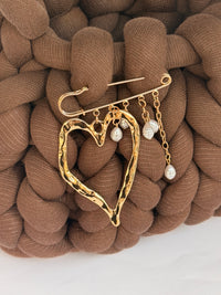 Angled view of a chunky brown crochet bag in jumbo yarn with a gold heart brooch