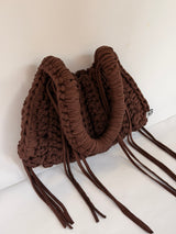 Close view of the woven Blessed label on a deep brown crochet shoulder bag