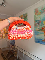Bright orange crochet clutch with a peach, pink and cream fringe