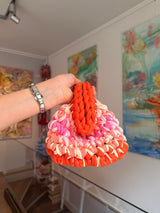 Bright orange crochet clutch with a peach, pink and cream fringe