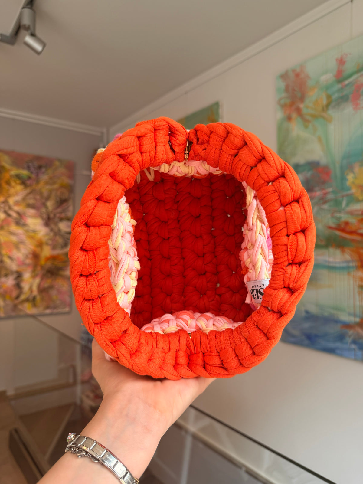 Bright orange crochet clutch with a peach, pink and cream fringe