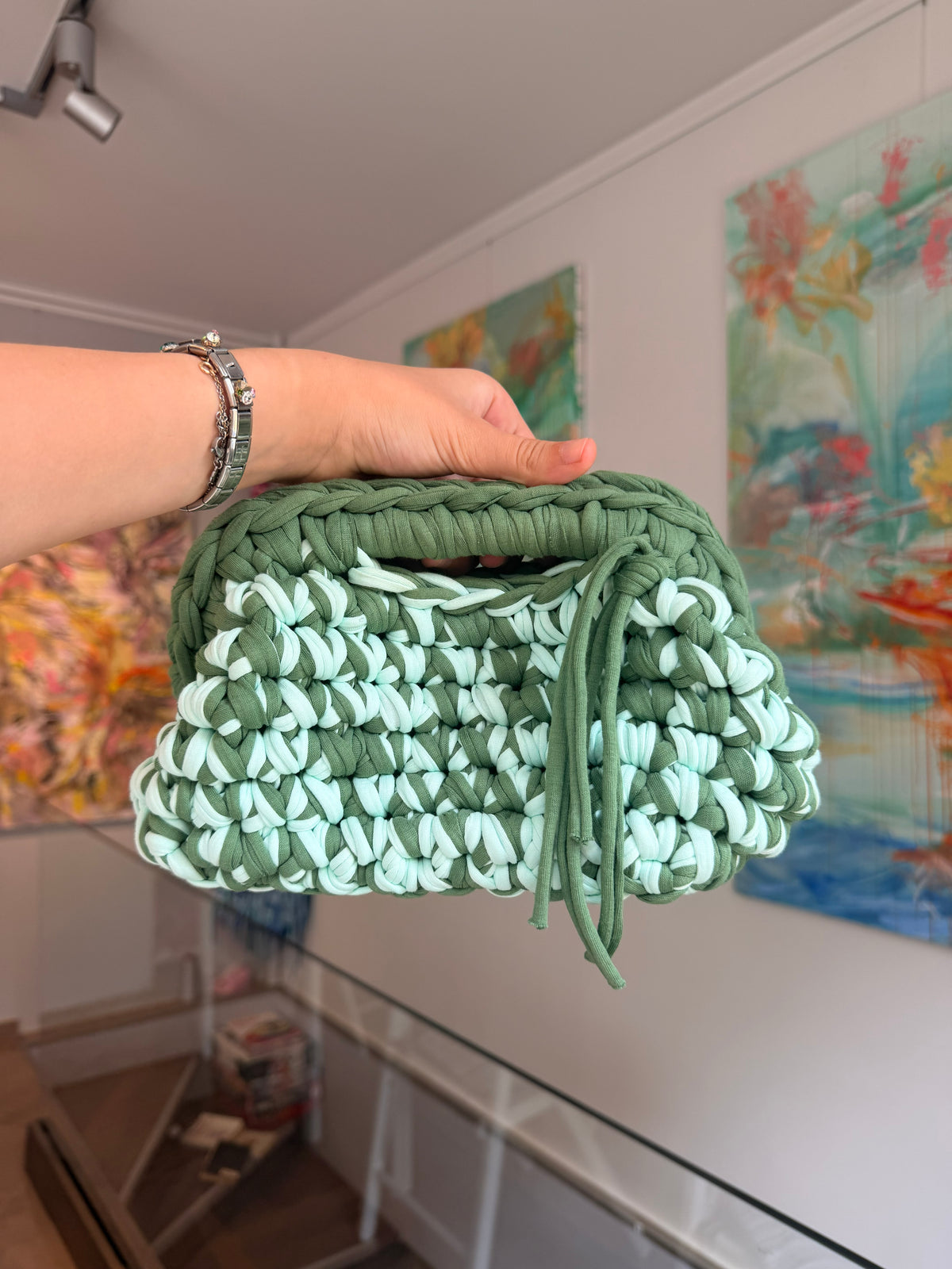 Soft green crochet clutch flecked with cream, with a twisted top handle