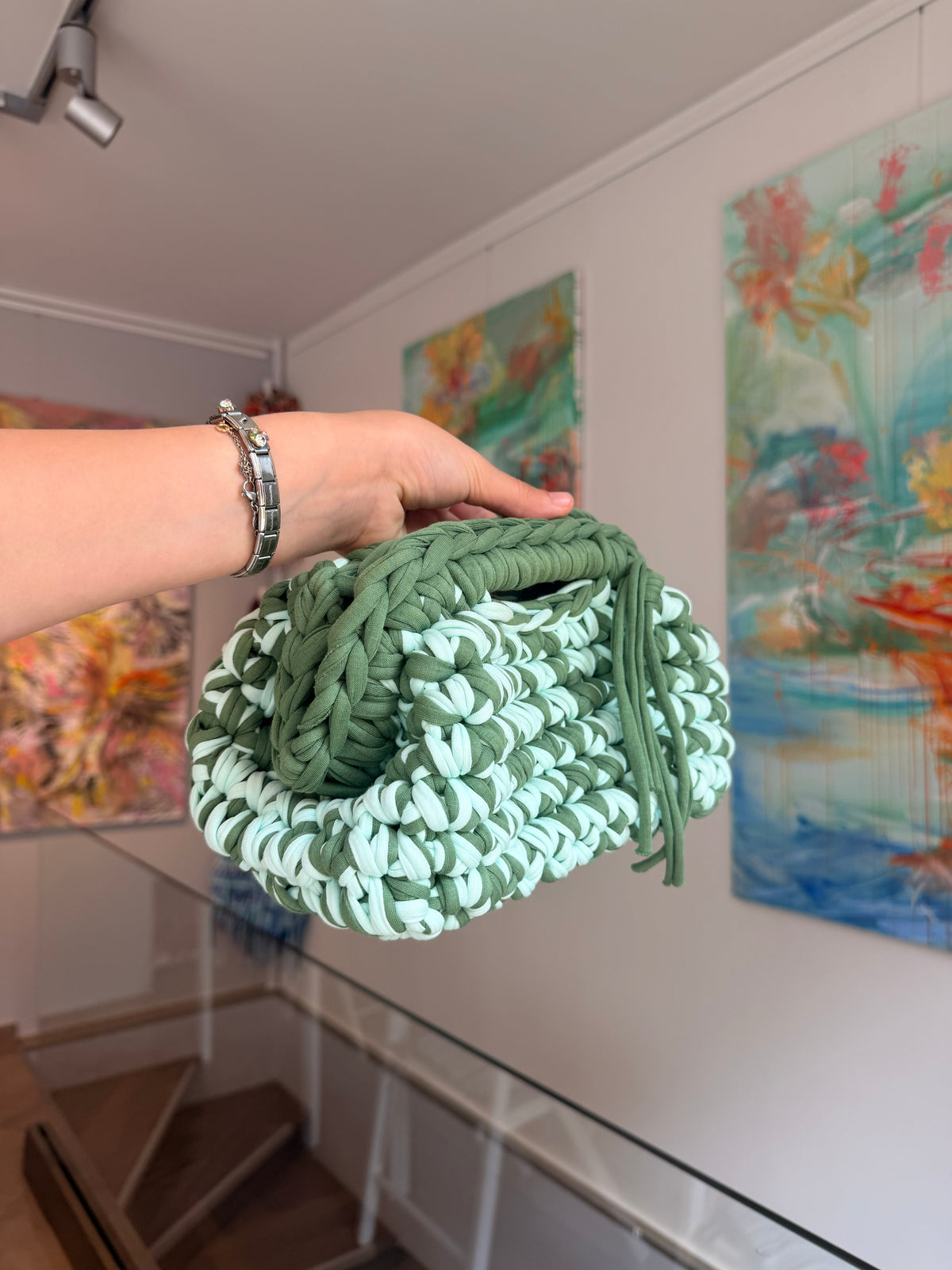 Soft green crochet clutch flecked with cream, with a twisted top handle