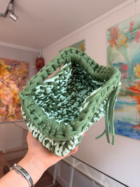 Soft green crochet clutch flecked with cream, with a twisted top handle