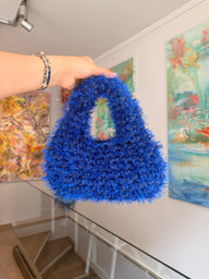 Electric blue crochet shoulder bag with an integrated cut-out handle