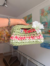 Sage green crochet clutch with a raspberry and cream stripe and a silk flower at the handle