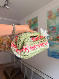 Sage green crochet clutch with a raspberry and cream stripe and a silk flower at the handle
