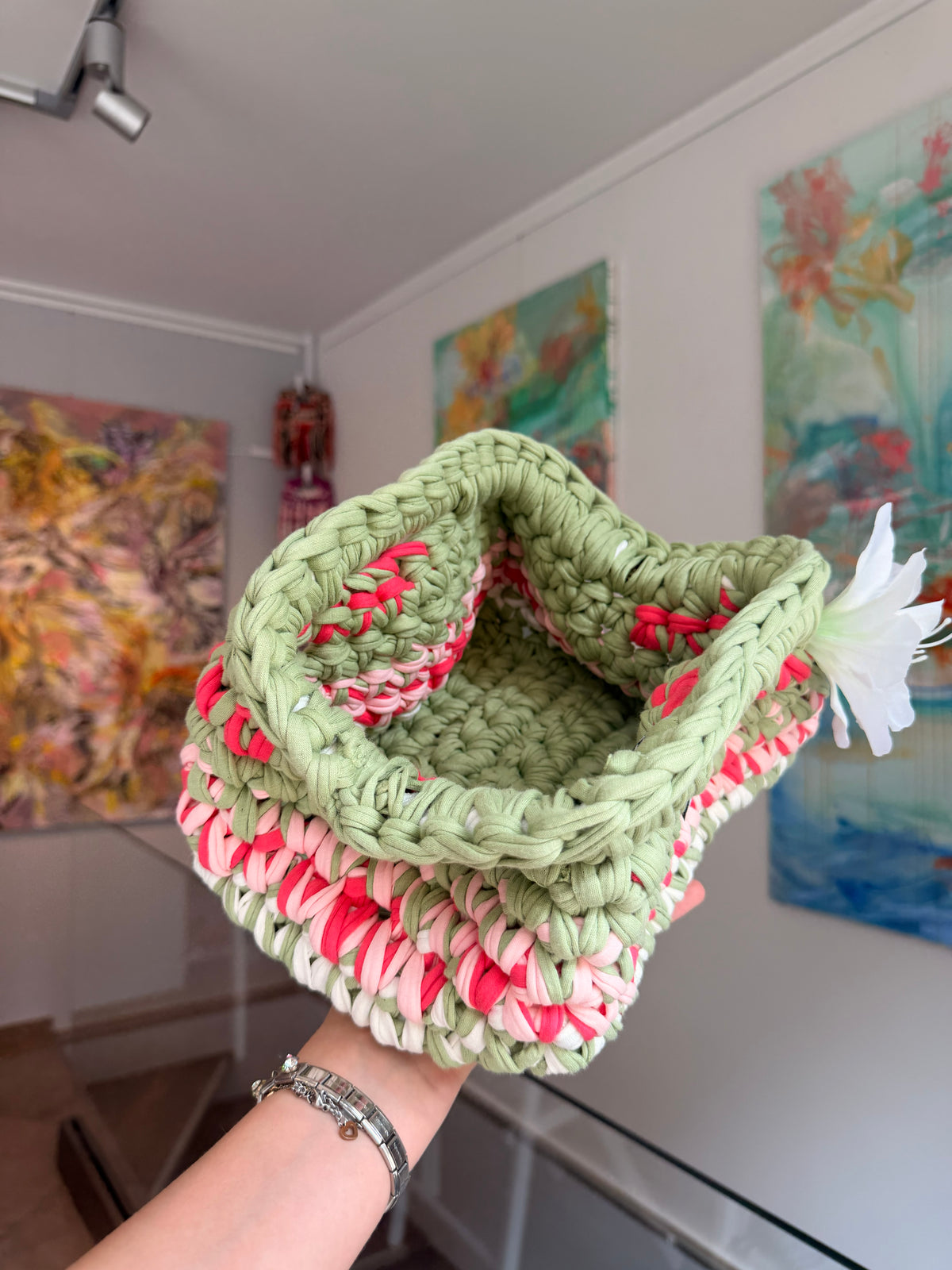 Sage green crochet clutch with a raspberry and cream stripe and a silk flower at the handle