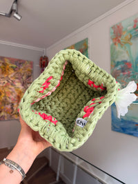 Sage green crochet clutch with a raspberry and cream stripe and a silk flower at the handle