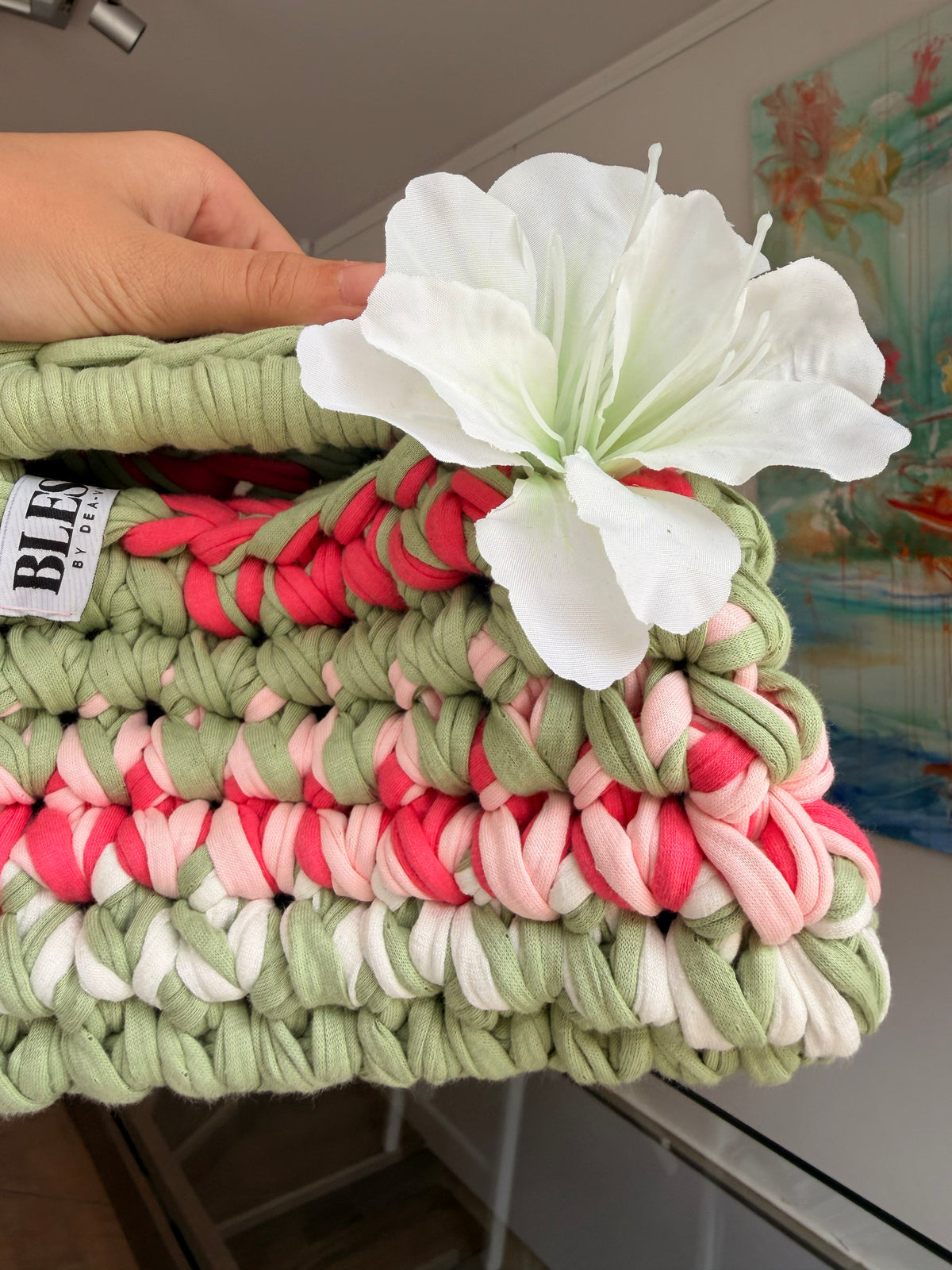 Sage green crochet clutch with a raspberry and cream stripe and a silk flower at the handle