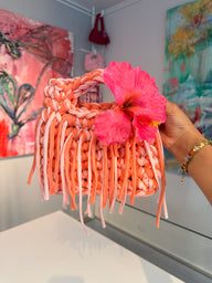 Coral and blush crochet bag with a braided top handle, long fringe and a pink hibiscus flower