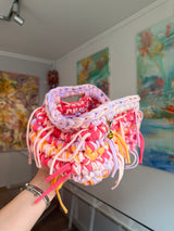 Multicoloured crochet clutch in coral, lilac, peach and apricot with a fringe all round