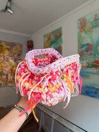 Multicoloured crochet clutch in coral, lilac, peach and apricot with a fringe all round