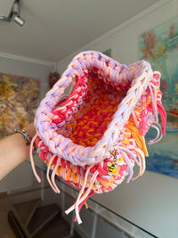 Multicoloured crochet clutch in coral, lilac, peach and apricot with a fringe all round