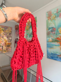 Bright red crochet shoulder bag with a braided top handle and long side ties